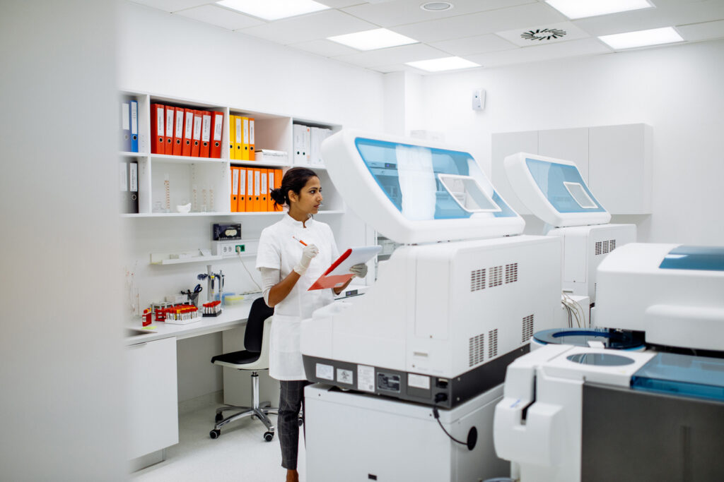 Scientist With Clipboard in Front of a Large Automated Centrifuge