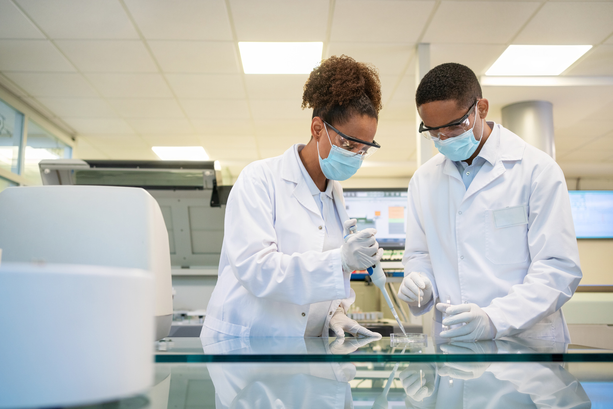 Two scientists conducting an experiment while wearing protective gear.