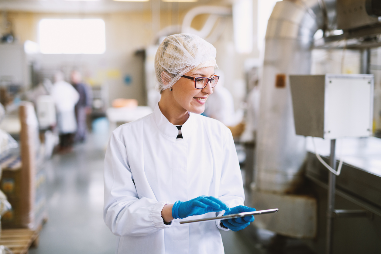 Smiling Worker Holding a Tablet in a Sterile Facility